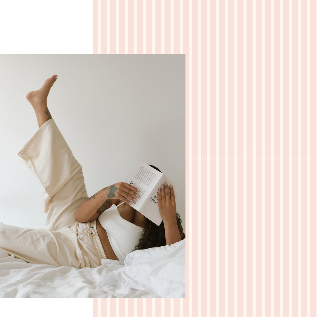 Person lying on a bed reading a book with a minimalistic background