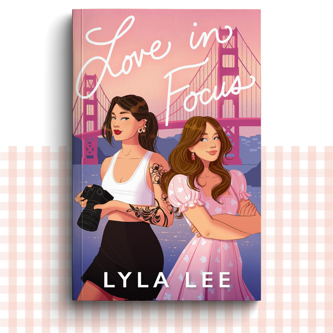 Paperback book cover of 'Love in Focus' by Lyla Lee with two women on the cover in front of a suspension bridge.