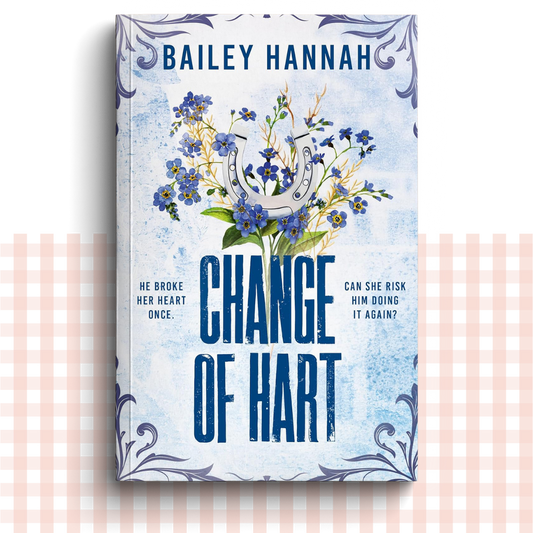 Paperback book cover of 'Change of Hart' by Bailey Hannah with flowers and horseshoe on a light blue background.