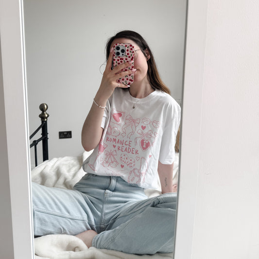 Person wearing a white t-shirt with text and graphics, standing in front of a mirror.