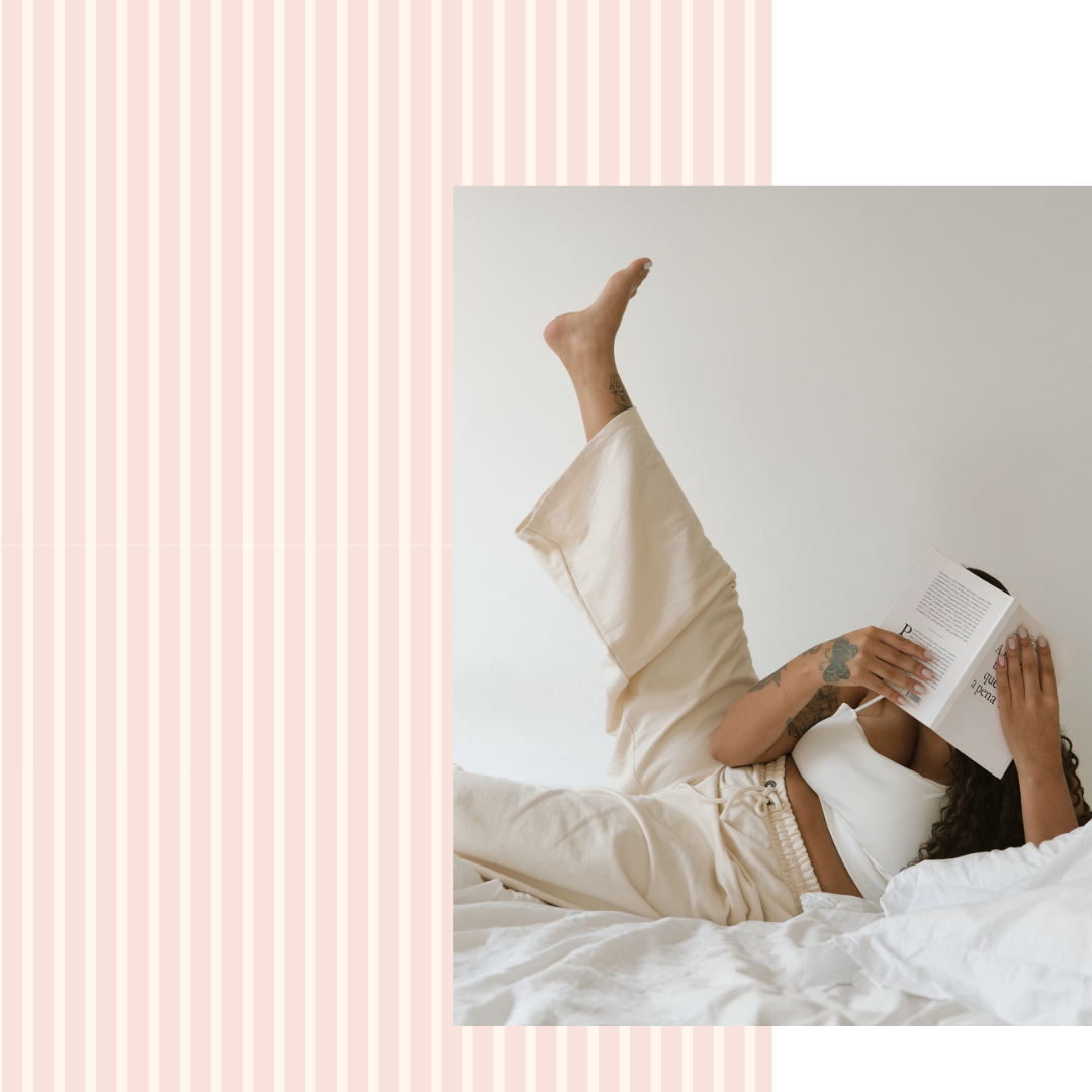 Person lying on a bed reading a book with a minimal background