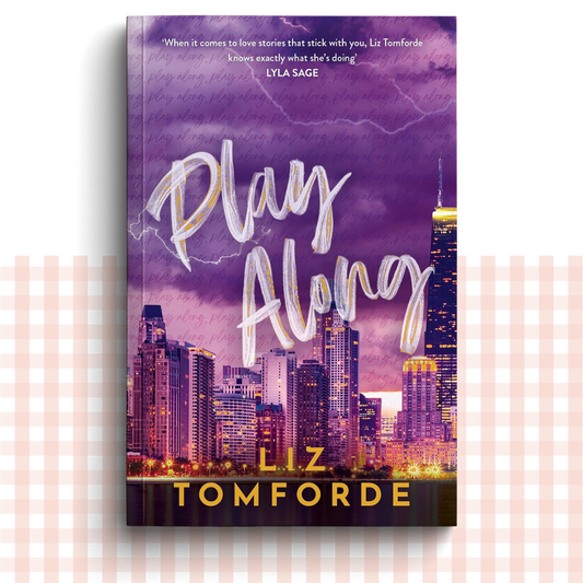 Paperback book cover of 'Play Along' by Liz Tomforde with a Chicago city skyline in the background.